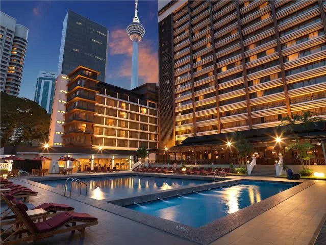 Teak sun loungers with outdoor cushions by a hotel pool